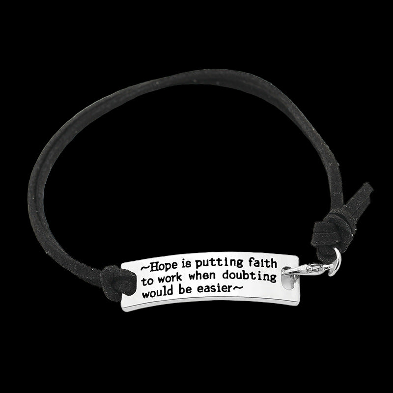 Black cord bracelet with motivational quote charm on a white background