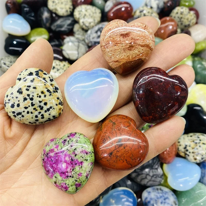 Hand holding heart-shaped polished stones with a colorful background