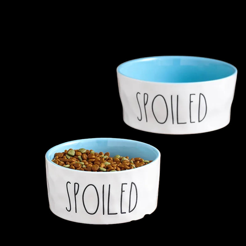 Two 'Spoiled' pet bowls with pet food on a wooden floor, featuring Good Housekeeping branding.