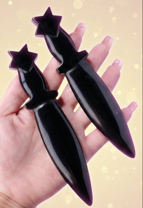 Black dagger-shaped objects held in a hand on a light background