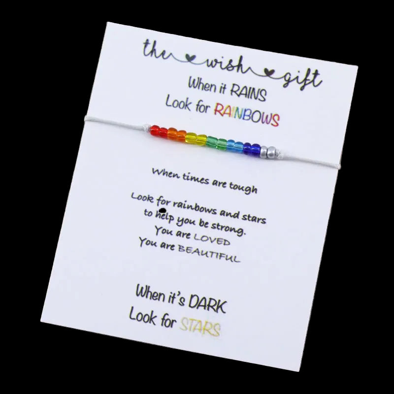 Rainbow beaded bracelet on a card with motivational text on a wooden surface