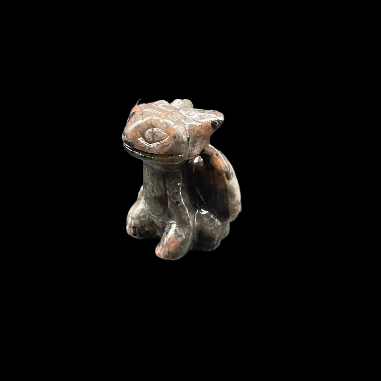 Small ceramic frog figurine on a dark surface