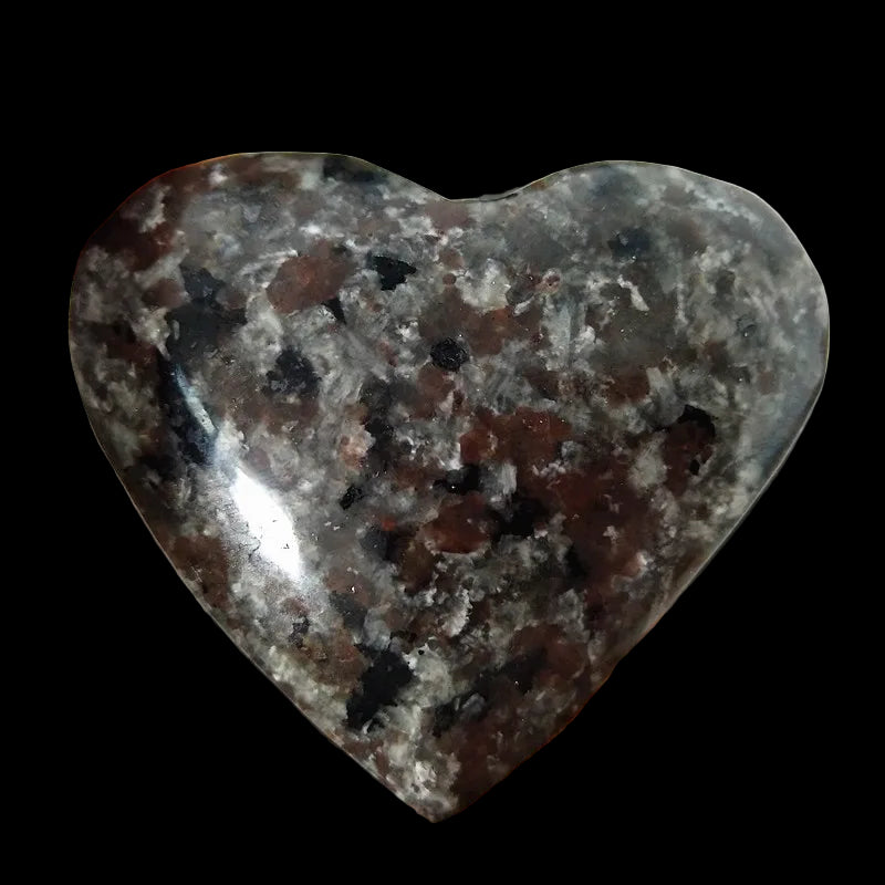 Heart-shaped dark stone held in a hand with more stones in the background