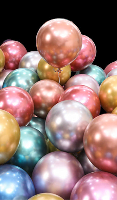 Colorful balloons in various sizes and colors with a table and plants in the background.