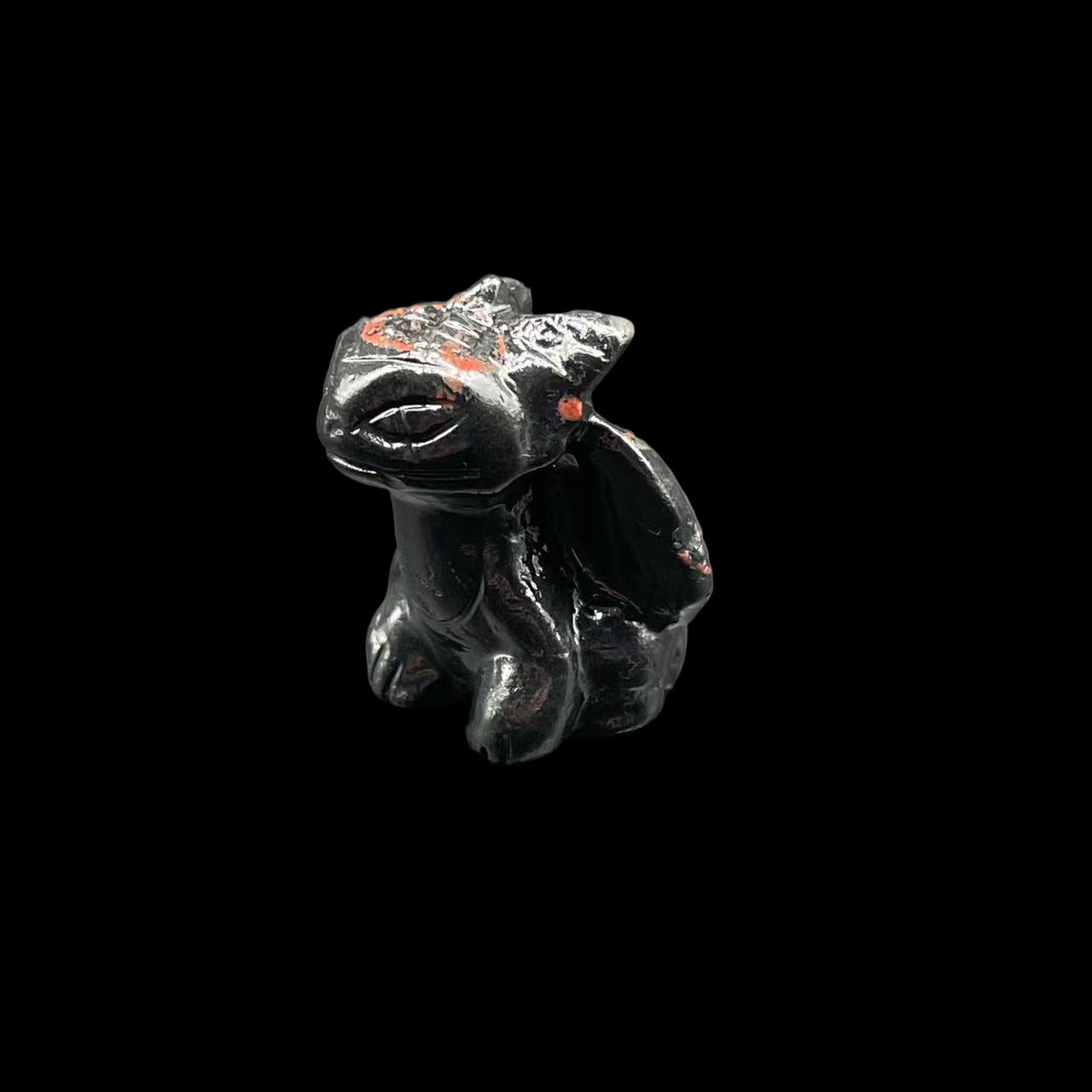 Small black figurine of a creature on a gray surface