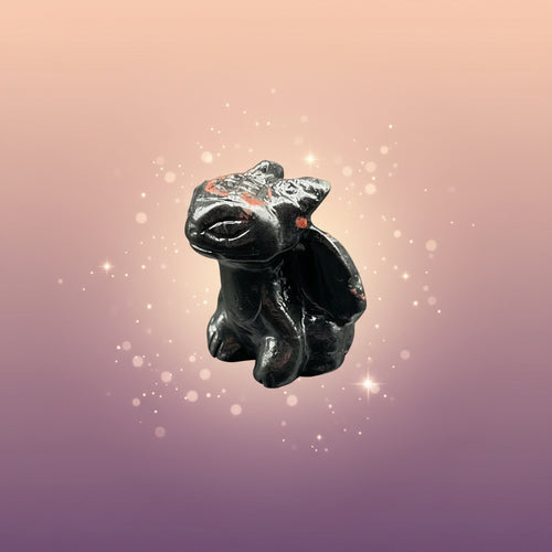 Small black figurine of a creature on a gray surface