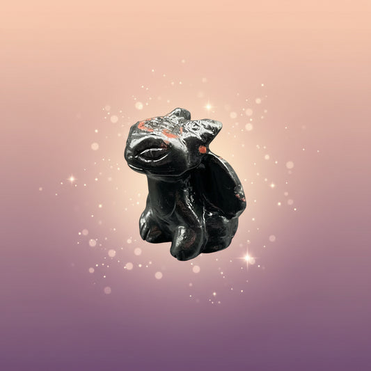 Small black figurine of a creature on a gray surface