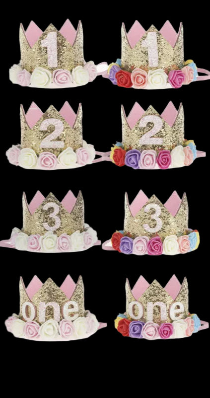 Baby wearing a pink and gold crown with floral decorations, surrounded by similar crowns with numbers and the word 'one'.