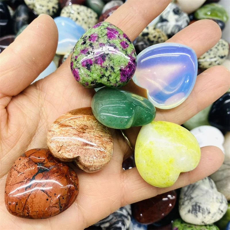 Hand holding various colorful gemstones with a blurred background of more stones.