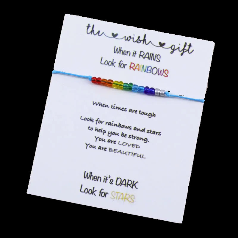 Rainbow beaded bracelet on a card with motivational text on a wooden surface