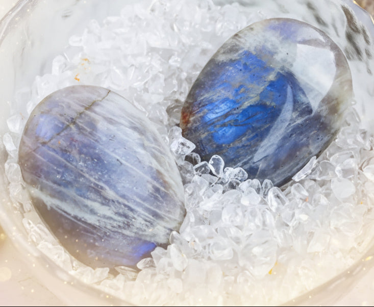 Polished labradorite stones in a clear bowl with sand