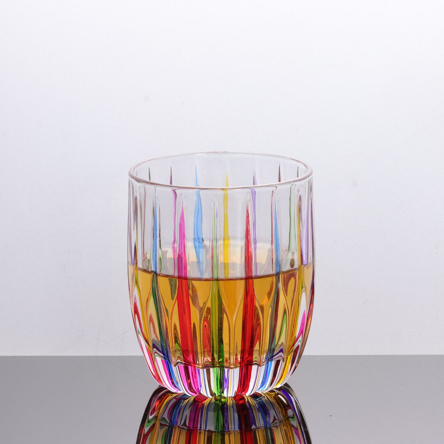 Multicolored glass with colorful liquid on a reflective surface