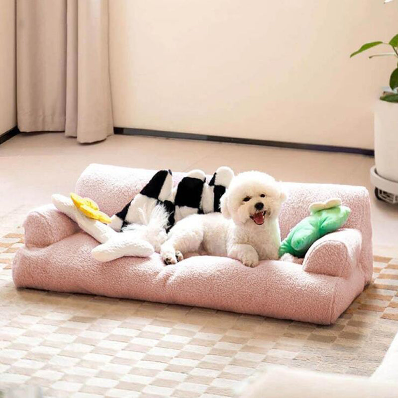 Two dogs on a pink pet bed with toys in a room.