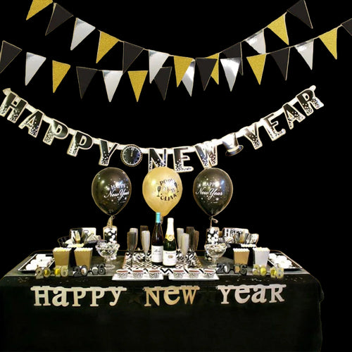 New Year's Eve celebration setup with table decorations, balloons, and a 'Happy New Year' banner.