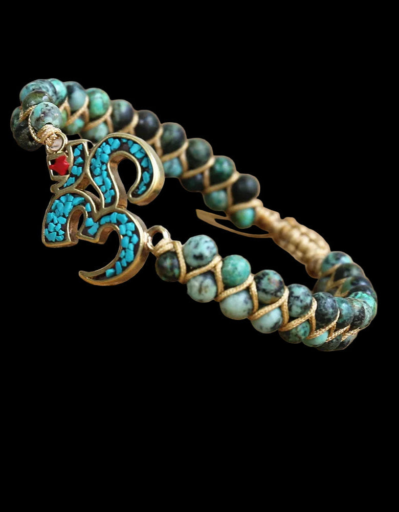 Bracelet with turquoise and black beads and a decorative clasp on a wooden surface.