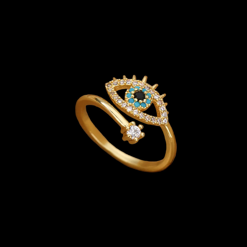 Gold ring with eye design on a beige fabric background