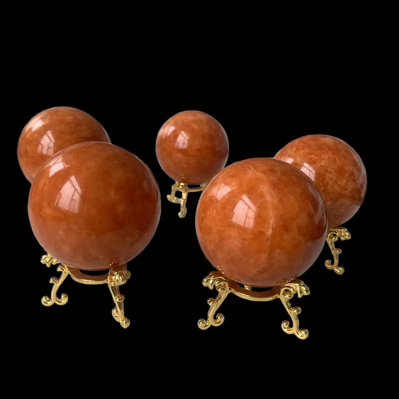 Five orange spherical objects on gold stands on a white surface with a blurred background.
