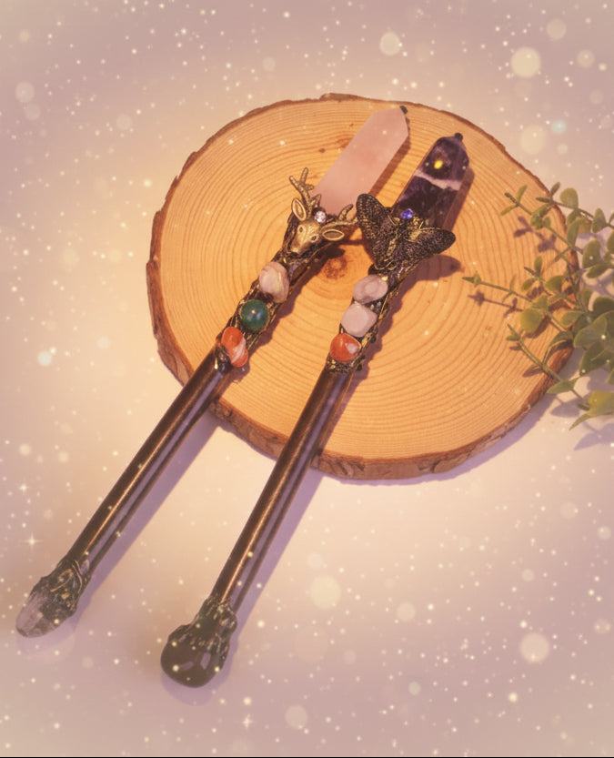 Two decorative sticks with gemstones on a wooden surface