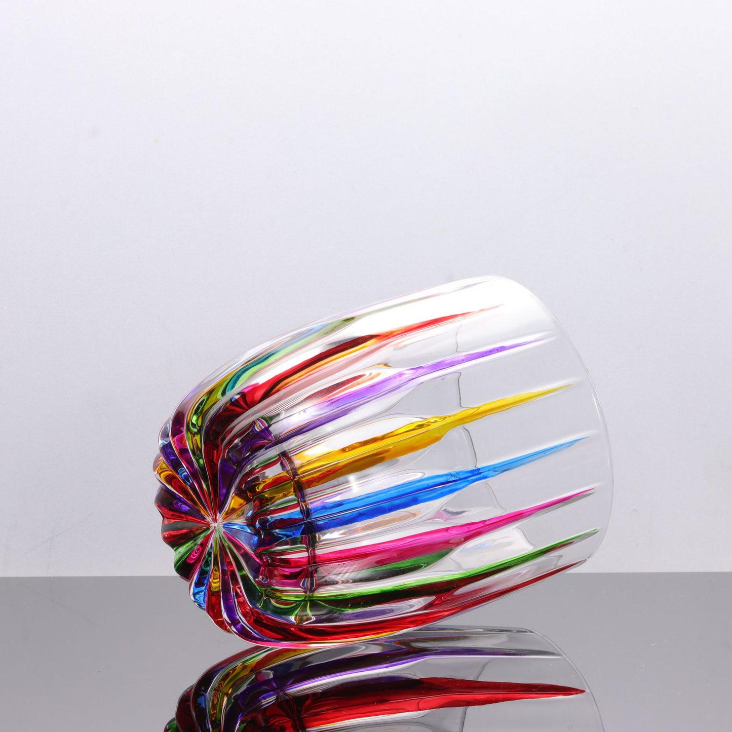 Colorful glass sculpture on a reflective surface with a light gray background