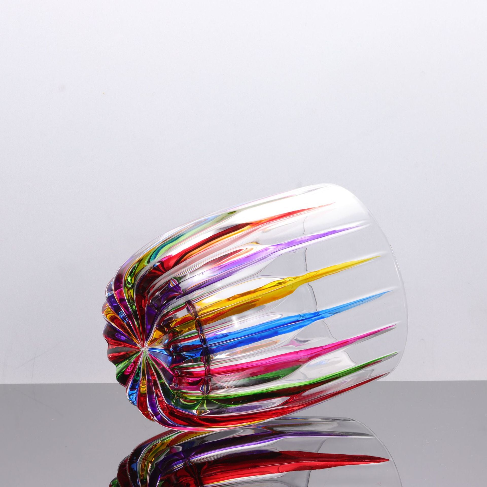 Colorful glass sculpture on a reflective surface with a light gray background