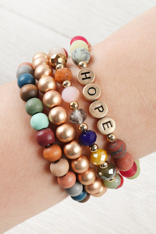 Colorful beaded bracelet with 'HOPE' charm on a wrist against a white background