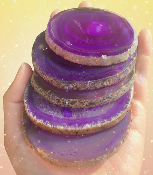 Stack of purple agate slices held in a hand with a natural background
