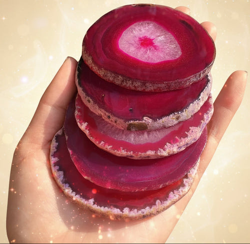 Stack of pink agate slices held in a hand with a natural background