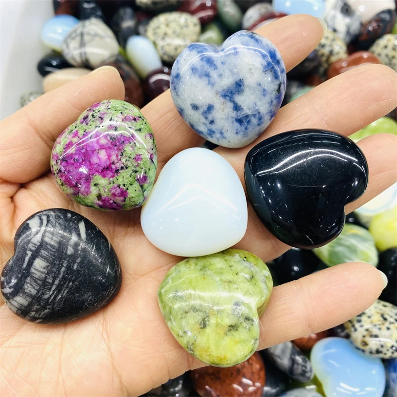 Hand holding various heart-shaped stones with a colorful background