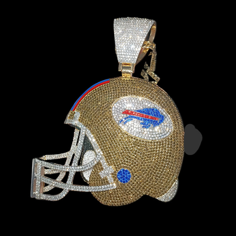 Gold helmet-shaped clutch with rhinestone embellishments held by a hand against a dark background