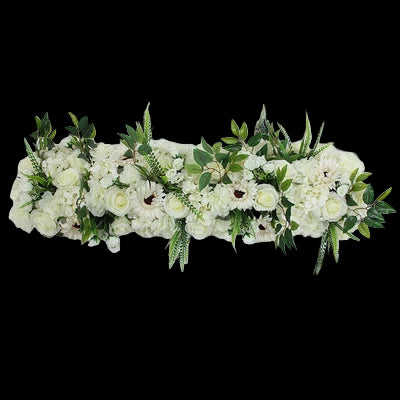 Floral arrangement with white flowers and green leaves on a light gray background