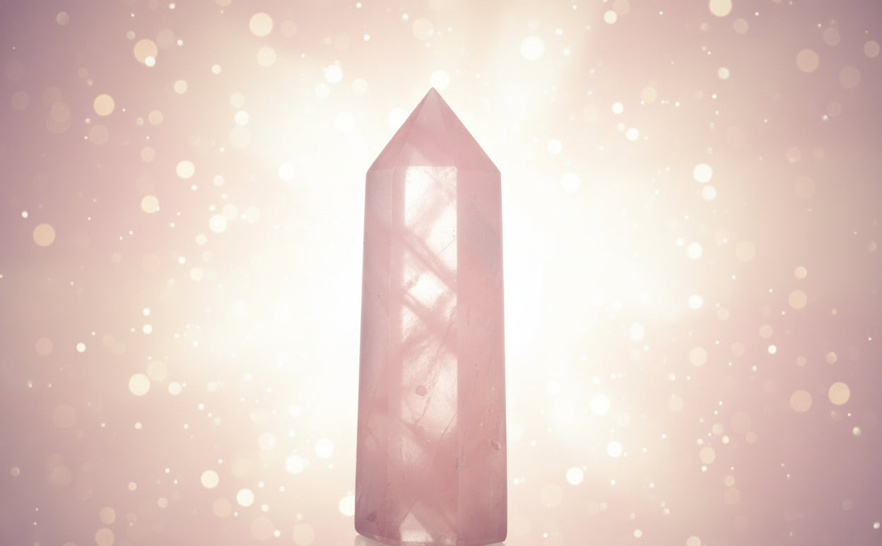 Pink crystal tower on a white surface with a blurred background
