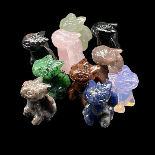 Collection of colorful cat-shaped crystal figurines on a gray background
