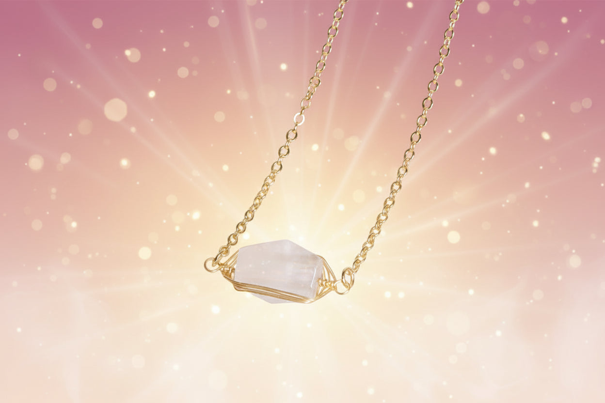 Gold necklace with a clear stone pendant on a beige background