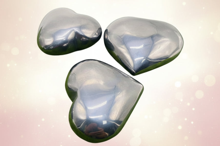 Three metallic stones on a grassy surface with flowers in the background