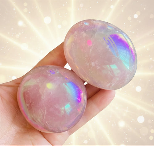 Two iridescent gemstones held in a hand with a natural background