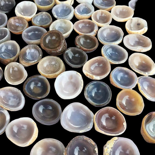 Collection of various agate stones with different colors and patterns on a light pink background.