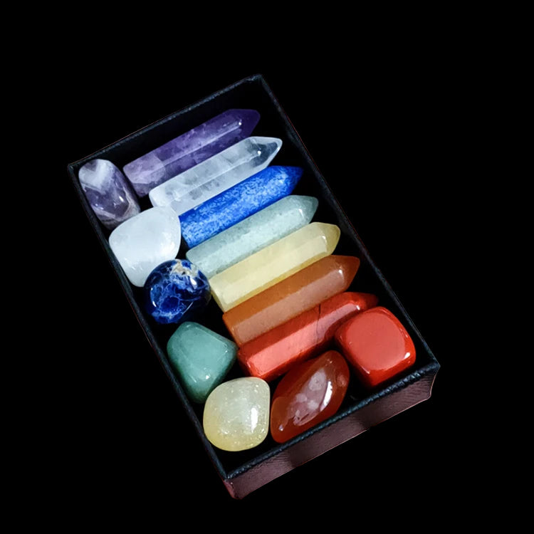 Hand holding a small black box filled with colorful crystals on a white background