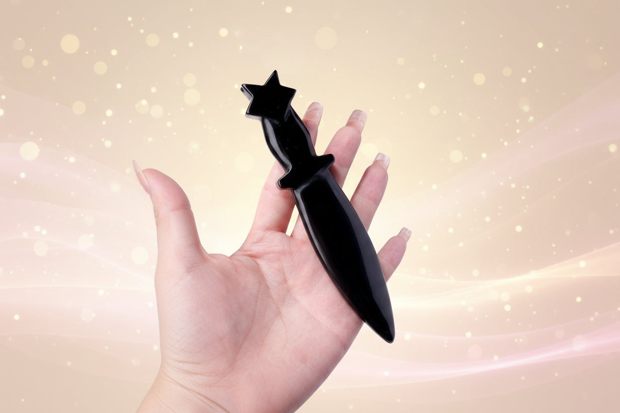 Black dagger-shaped bottle opener held in a hand with books in the background