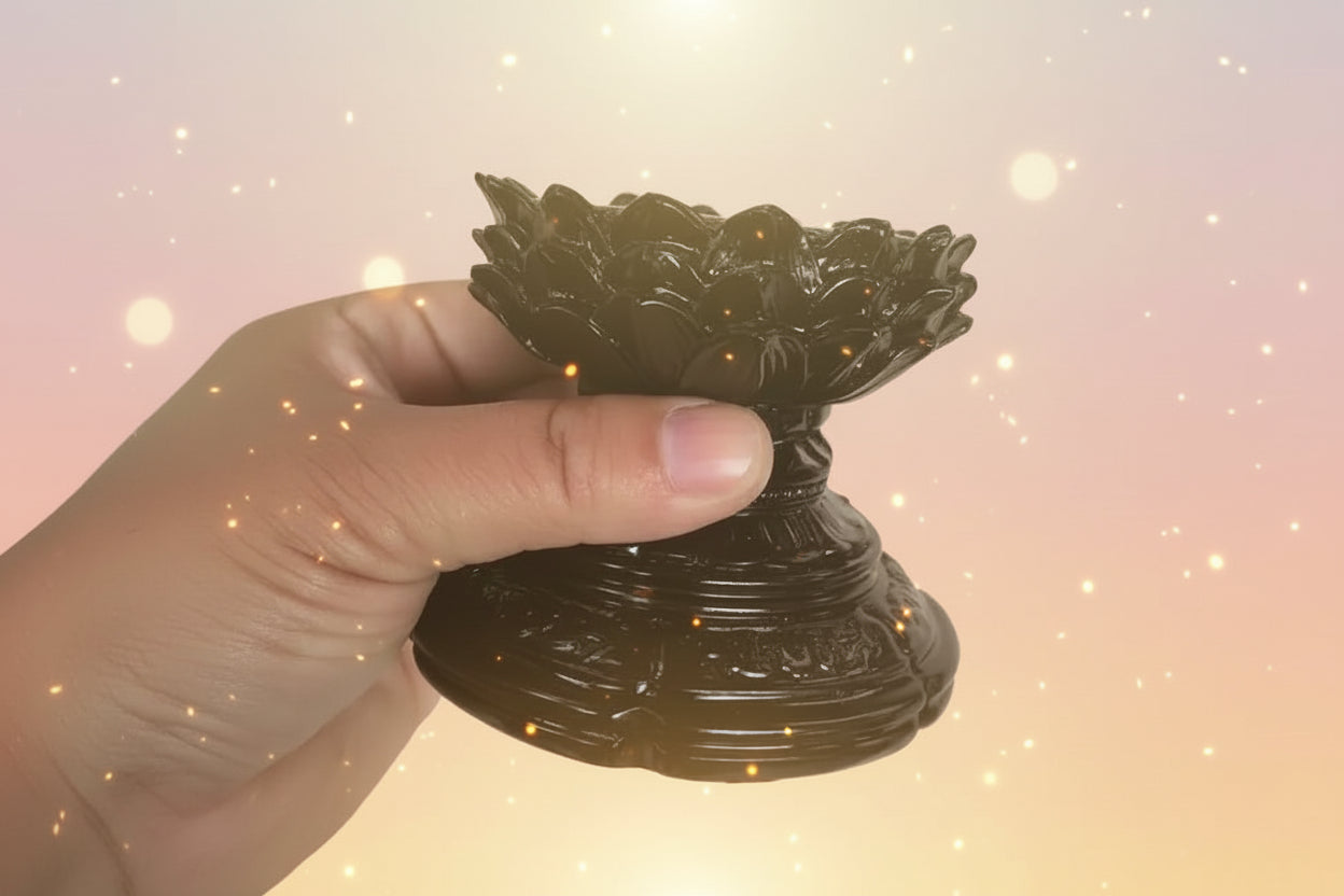 Black lotus-shaped object held by a hand on a white background