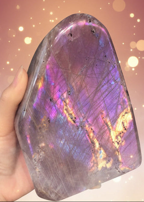 Hand holding a colorful iridescent stone with more stones in the background