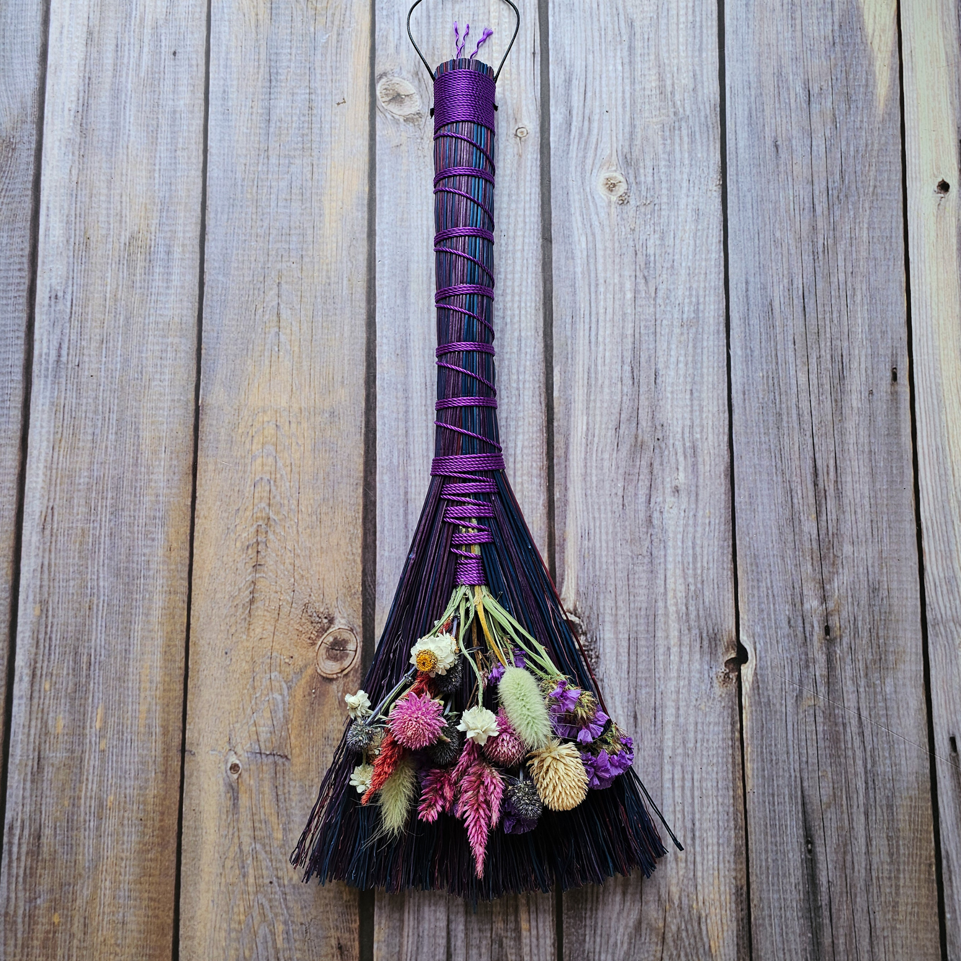 Decorative broom with flowers against a wooden background