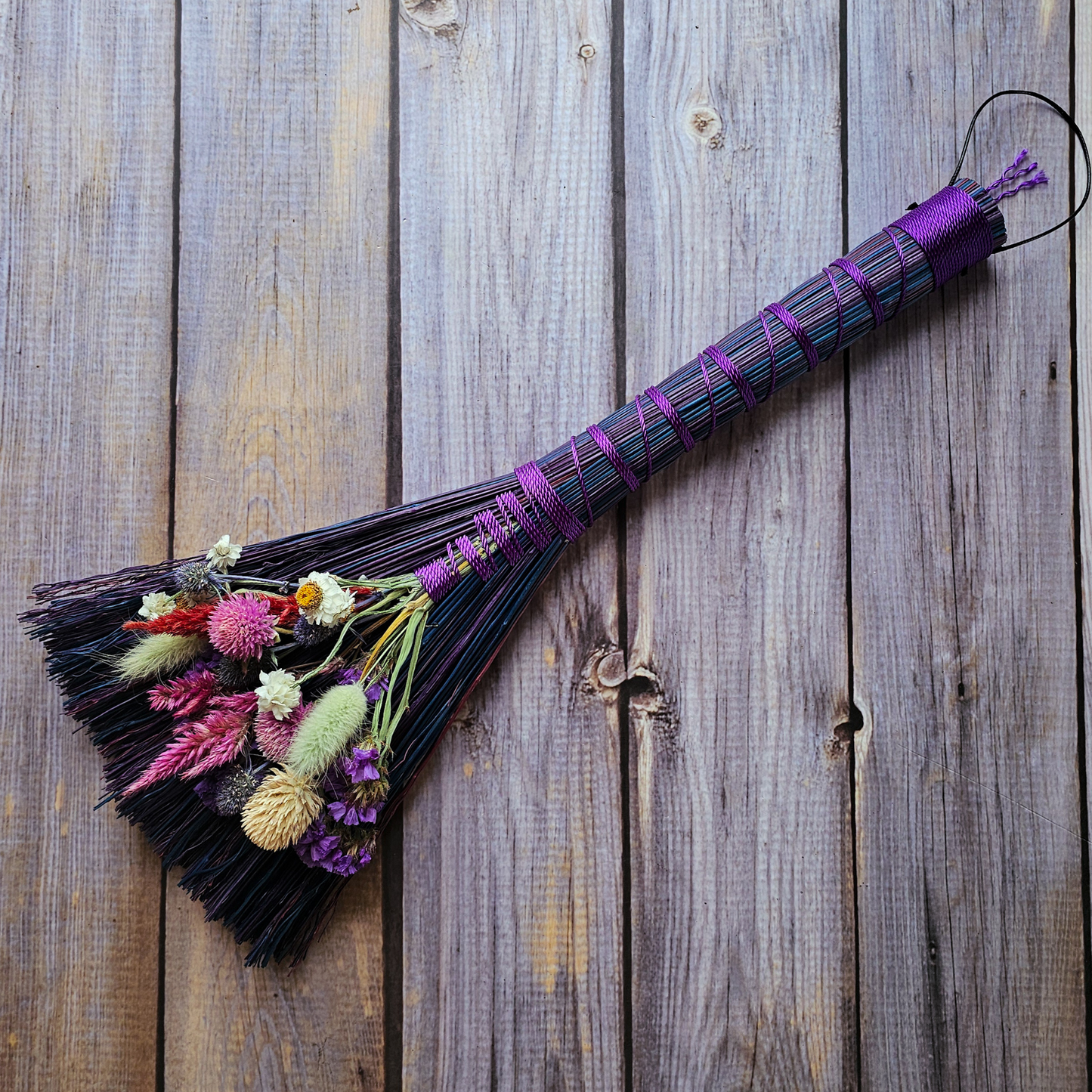 Decorative broom with flowers on a wooden surface