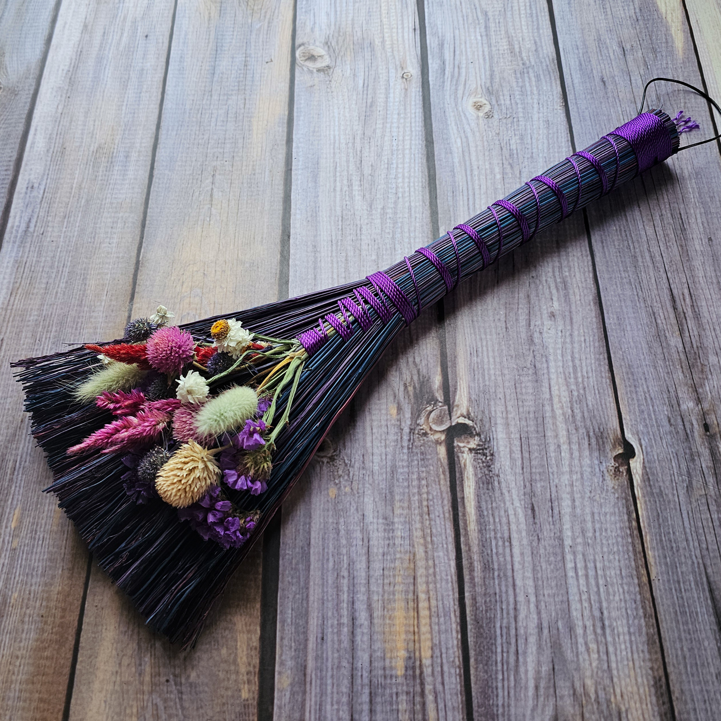 Decorative broom with flowers on a wooden surface