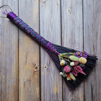 Decorative broom with floral attachments on a wooden surface