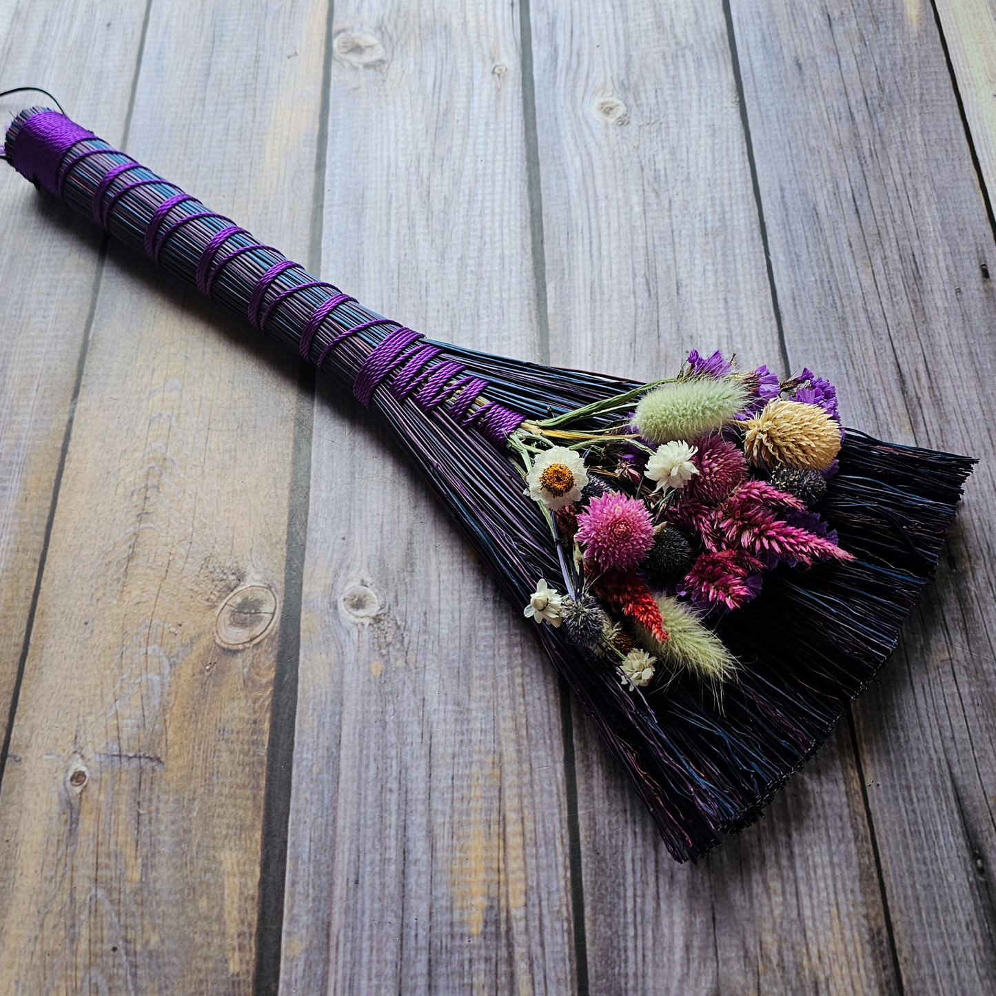 Decorative broom with flowers on a wooden surface