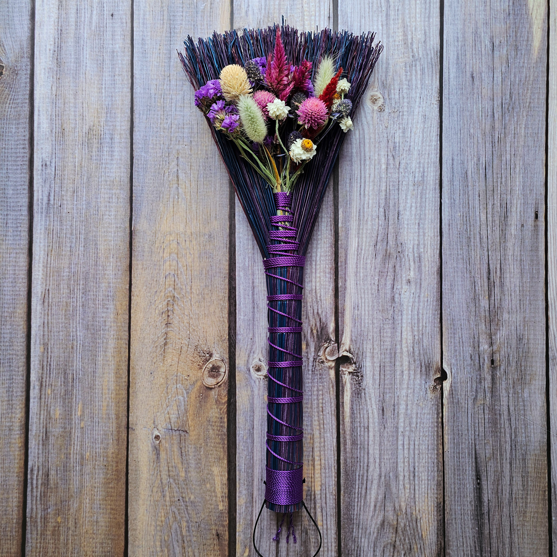 Decorative broom with flowers on a wooden background