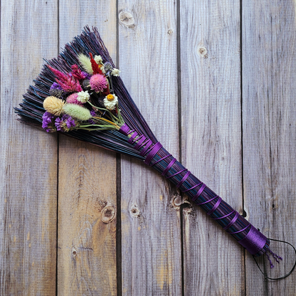 Decorative broom with flowers on a wooden surface