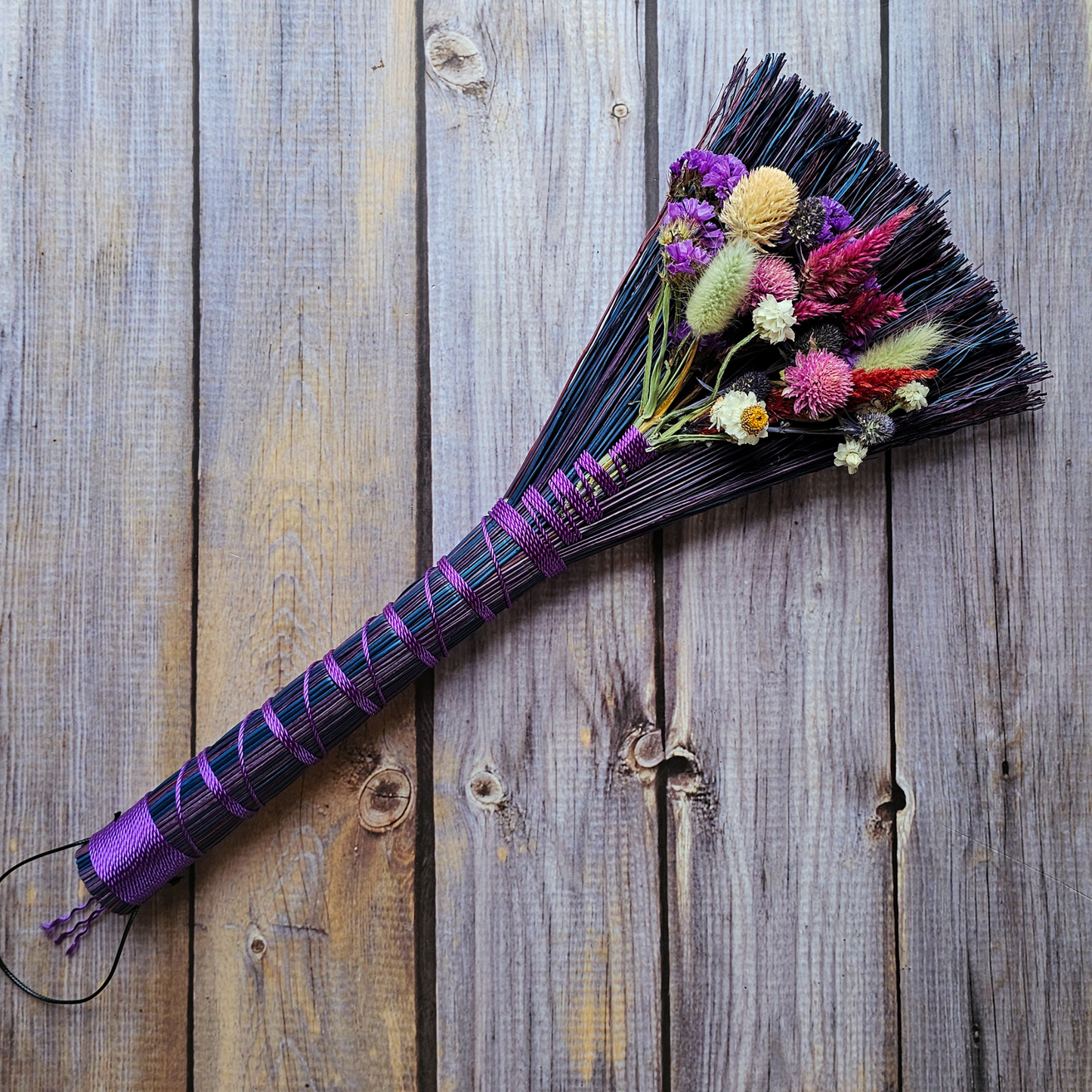 Decorative broom with flowers on a wooden surface