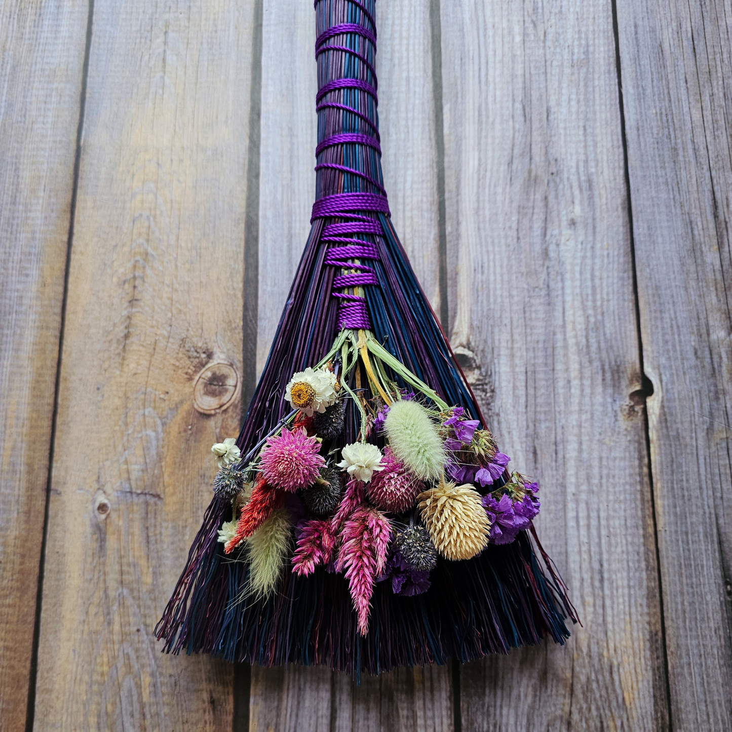 Decorative broom with flowers against a wooden background