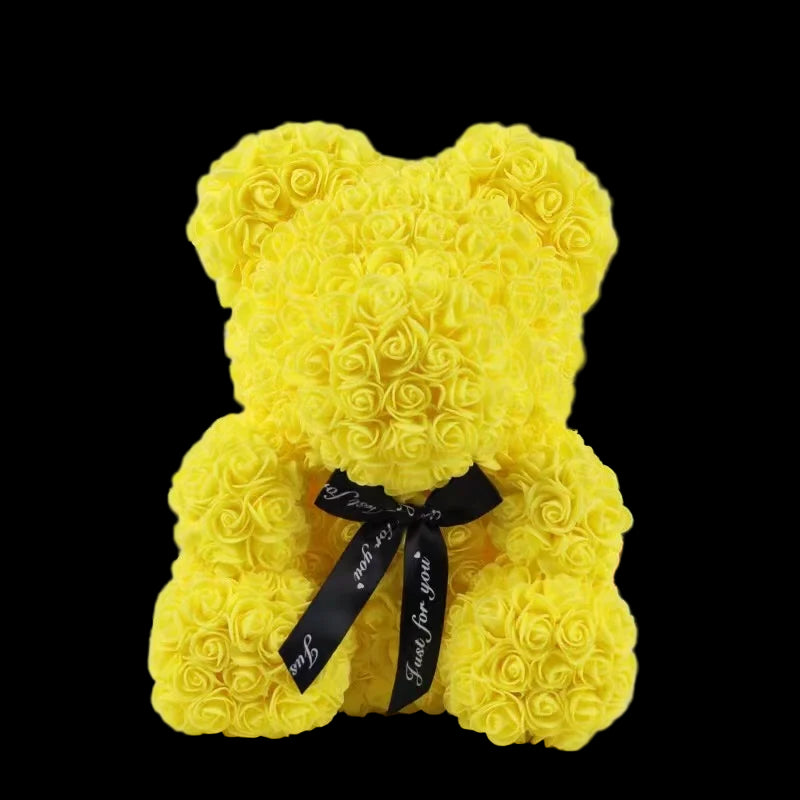 Yellow teddy bear made of rose petals with a black bow on a white background